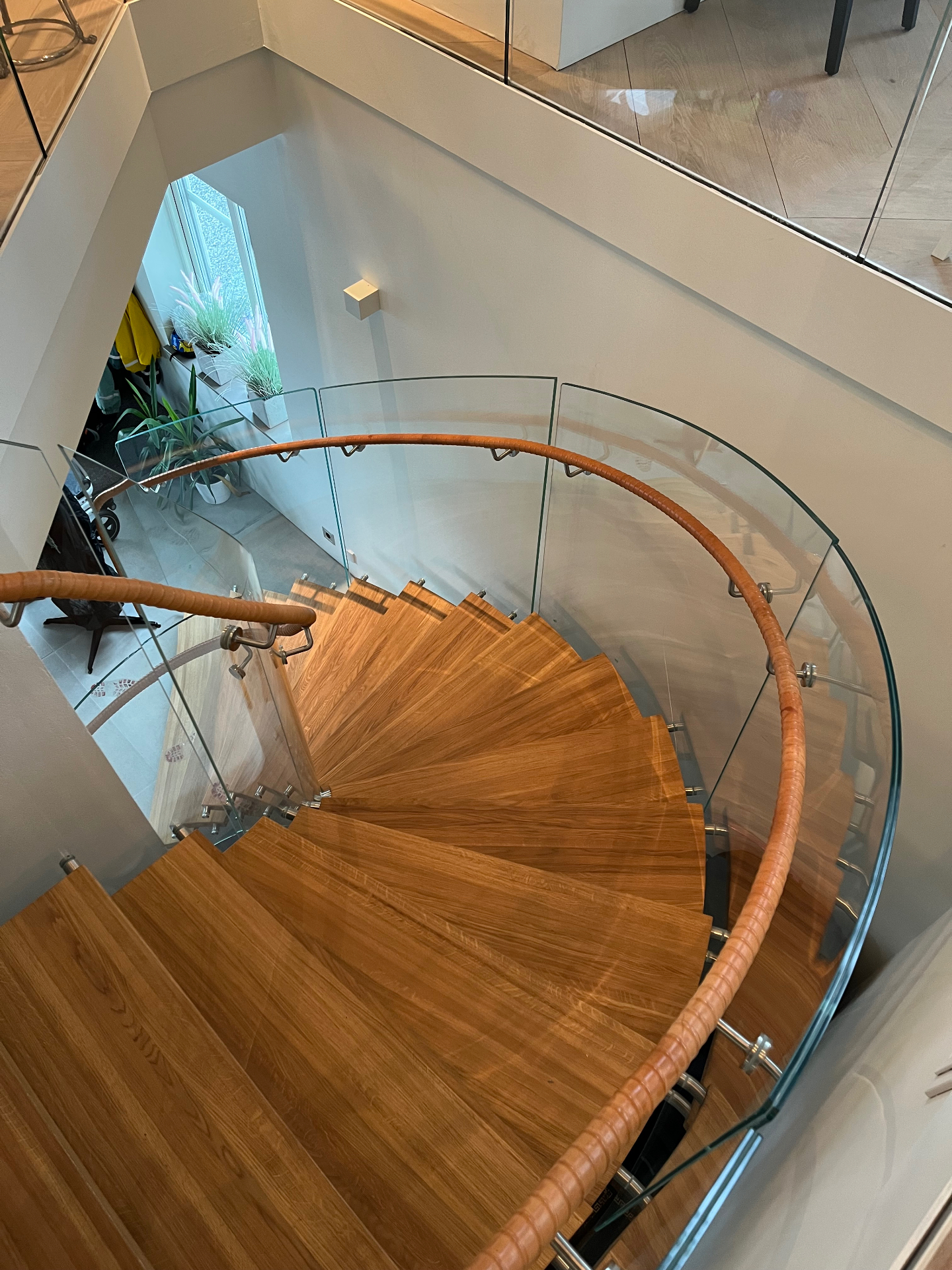 Spiraltrappa i ek med böjt glasräcke och läderklädd ledstång