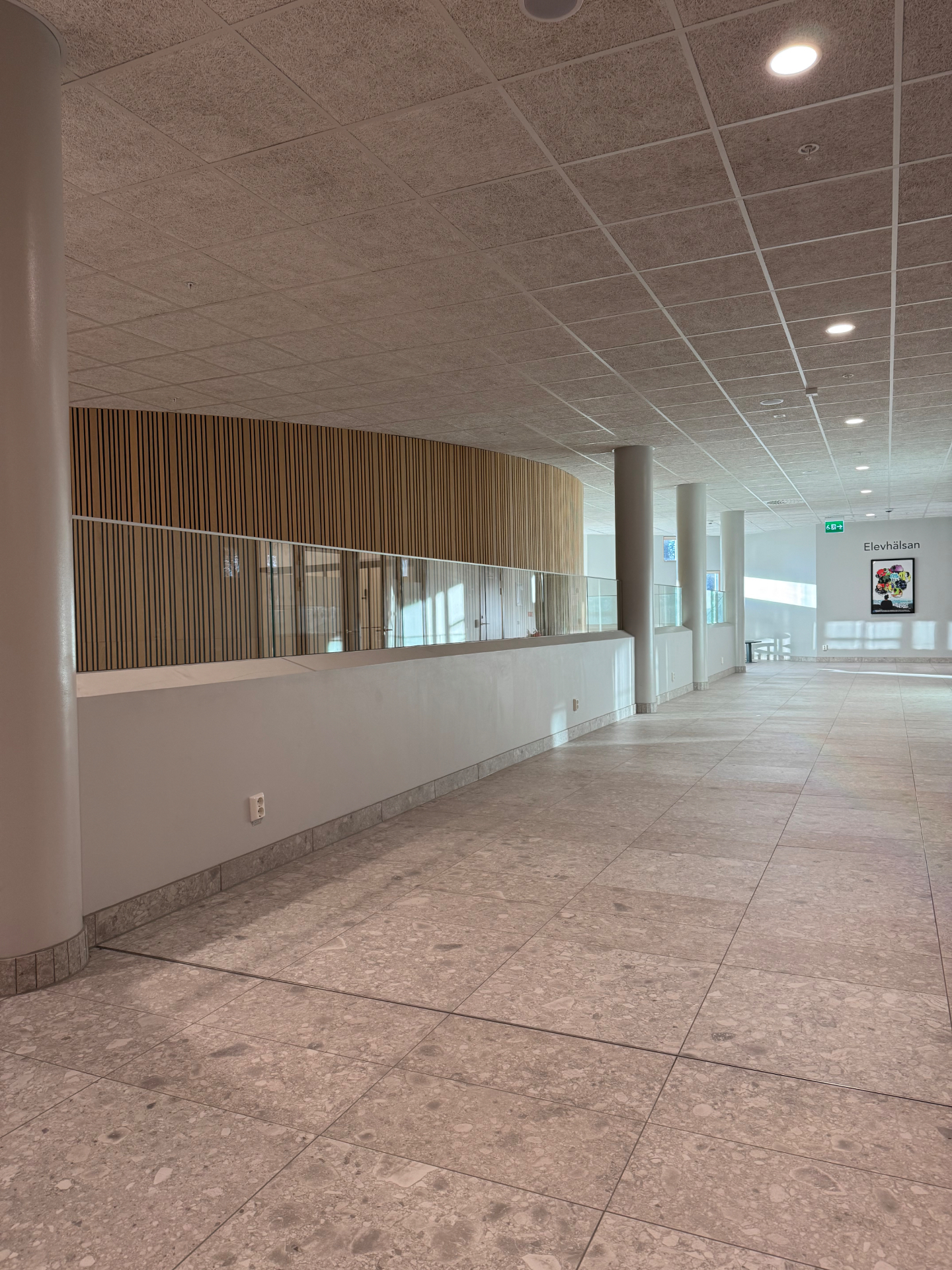 Ramlöst glasräcke i skolans ljusa korridor