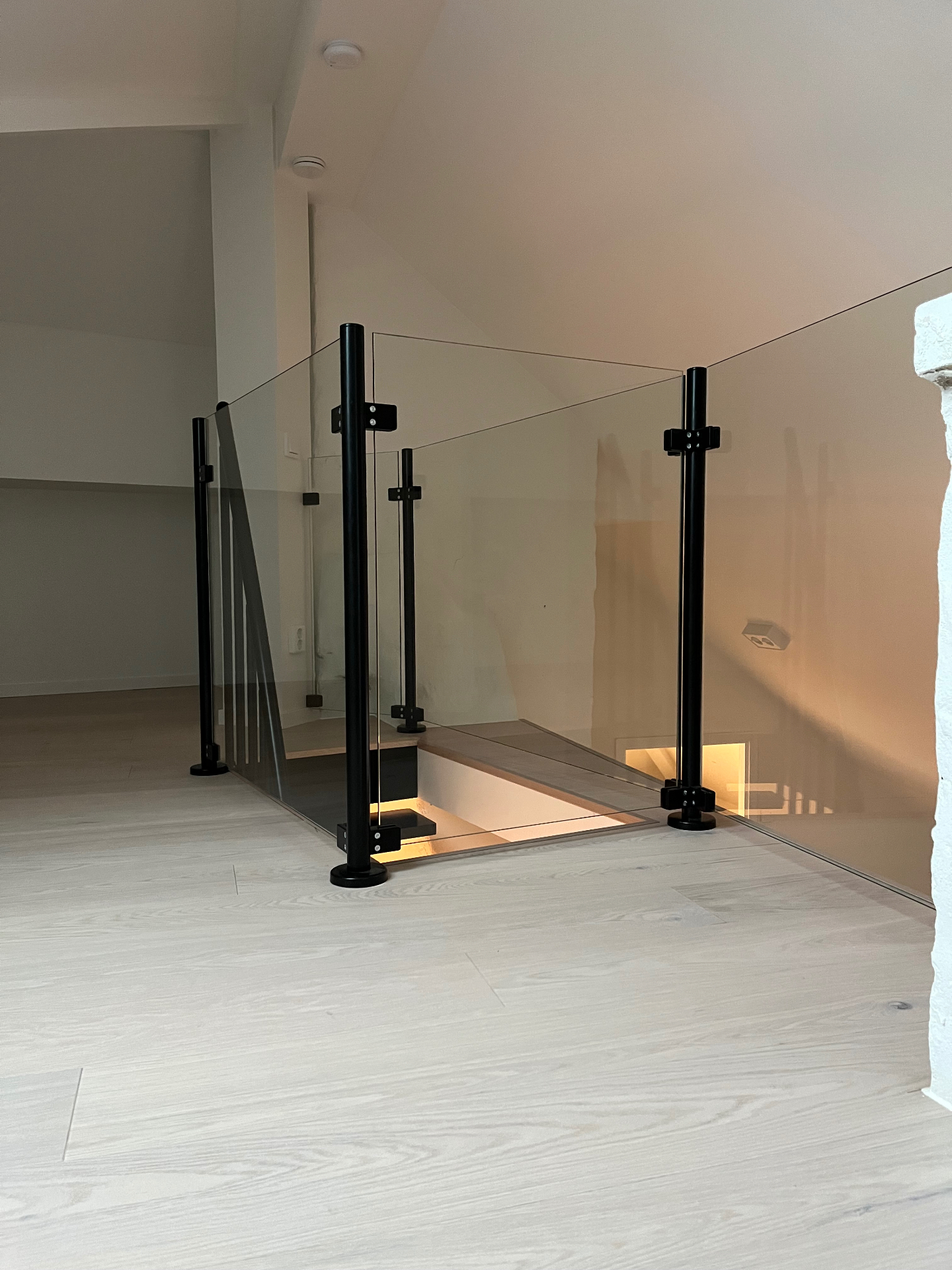 Glasräcke med svarta stolpar runt trapputrymme i hall